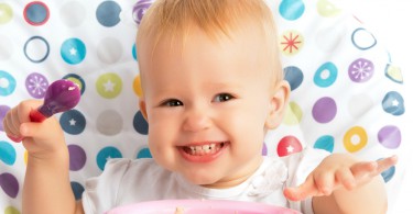 cheerful-happy-baby-child-eats-itself-with-a-spoon