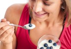 Portrait of Woman enjoying eating her yogurt and blueberries isolated on white background