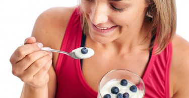 Portrait of Woman enjoying eating her yogurt and blueberries isolated on white background