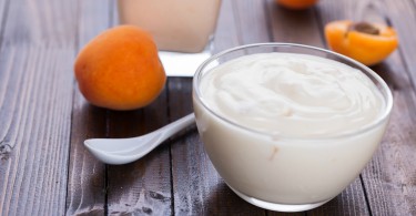 Yogurt with apricots in bowl on wooden background. Selective focus.
