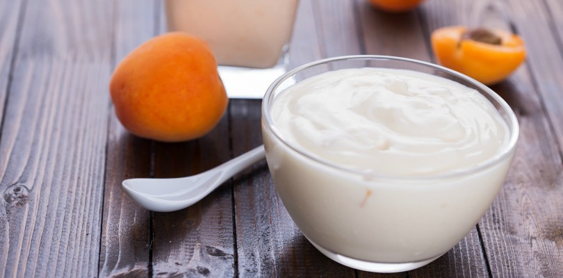 Yogurt with apricots in bowl on wooden background. Selective focus.