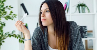 Portrait of beautiful young woman eating yogurt at home.